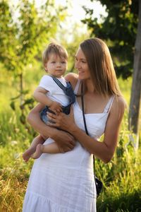 Happy woman in nature with baby boy with blonde hair in arms 