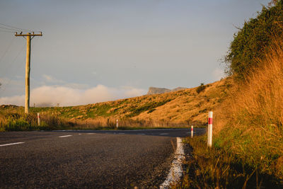 Empty road by land against sky