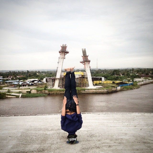 sky, lifestyles, leisure activity, full length, built structure, architecture, standing, technology, casual clothing, building exterior, young adult, holding, rear view, photography themes, travel, cloud - sky, photographing, tourism