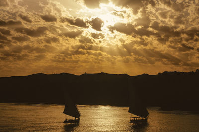 Cloudy sky with sunshine and traditional sailing boats called felucca on the nile river, in egypt