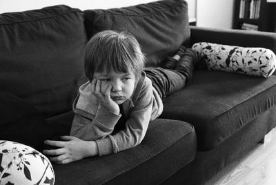 Cute boy lying down on sofa at home