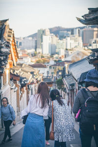 Rear view of people walking on street amidst buildings in city