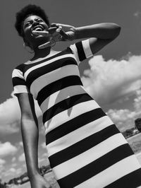 Low angle view of a beautiful woman standing against sky