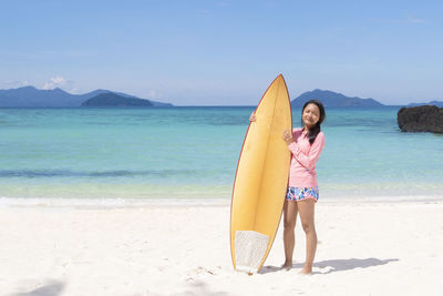 Rear view of woman with surfboard at beach