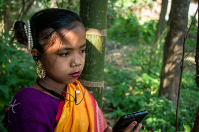 A tribal little girl is listening to music with bluetooth headphones on her android phone