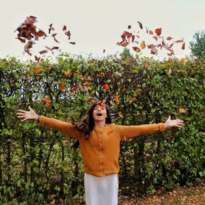 Young woman with arms outstretched standing on field