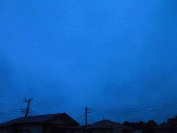 Low angle view of silhouette house against blue sky