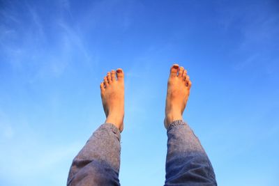 Low section of man against blue sky