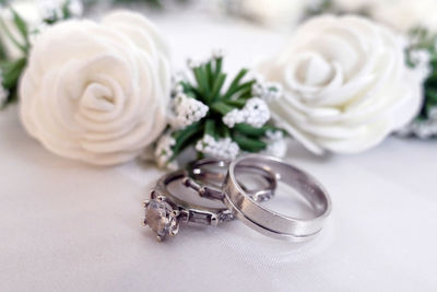 Close-up of white roses with rings on table