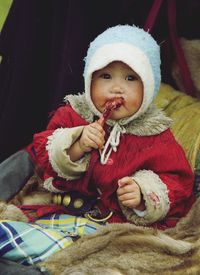 Portrait of cute baby girl eating chicken meat while sitting on stroller