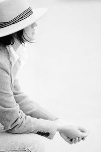 Rear view of woman wearing hat standing against white background