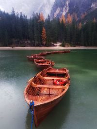 Boat moored on lake against trees