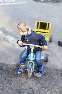 High angle view of boy looking backwards while riding tricycle