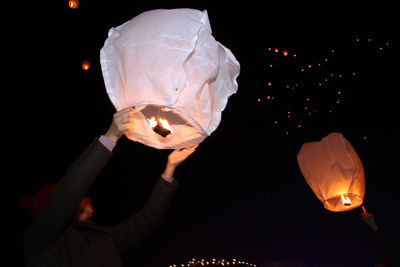 Midsection of person holding illuminated lantern at night