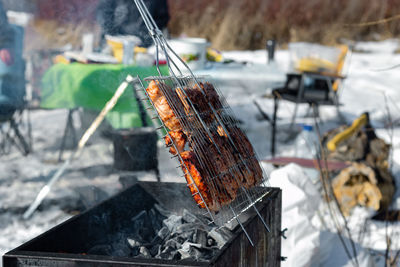 Winter barbecue outdoors, grill steak meat over hot coals in bbq at campsite cookout, camping mood