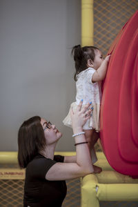 Side view of mother holding daughter standing on railing