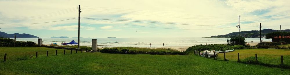 Scenic view of field by sea against sky