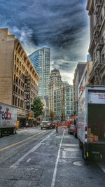 View of city street against cloudy sky