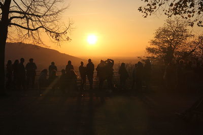 Silhouette people standing on mountain against sky during sunset