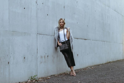 Full length of woman standing against wall