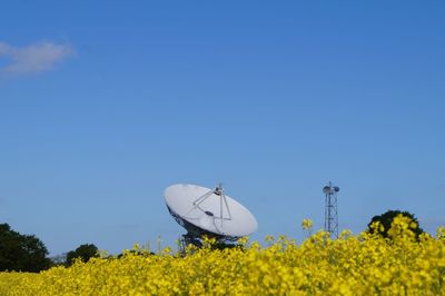 Scenic view of radio telescope in field against clear blue sky