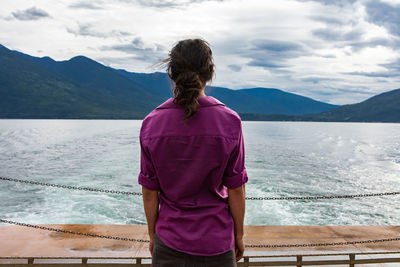 Rear view of woman looking at sea against mountains