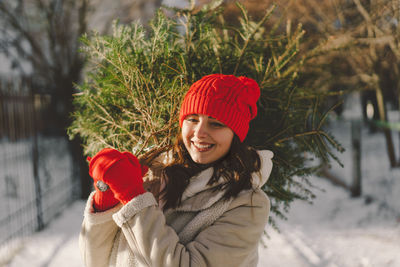 A beautiful girl in a red hat carries a christmas tree. christmas tree