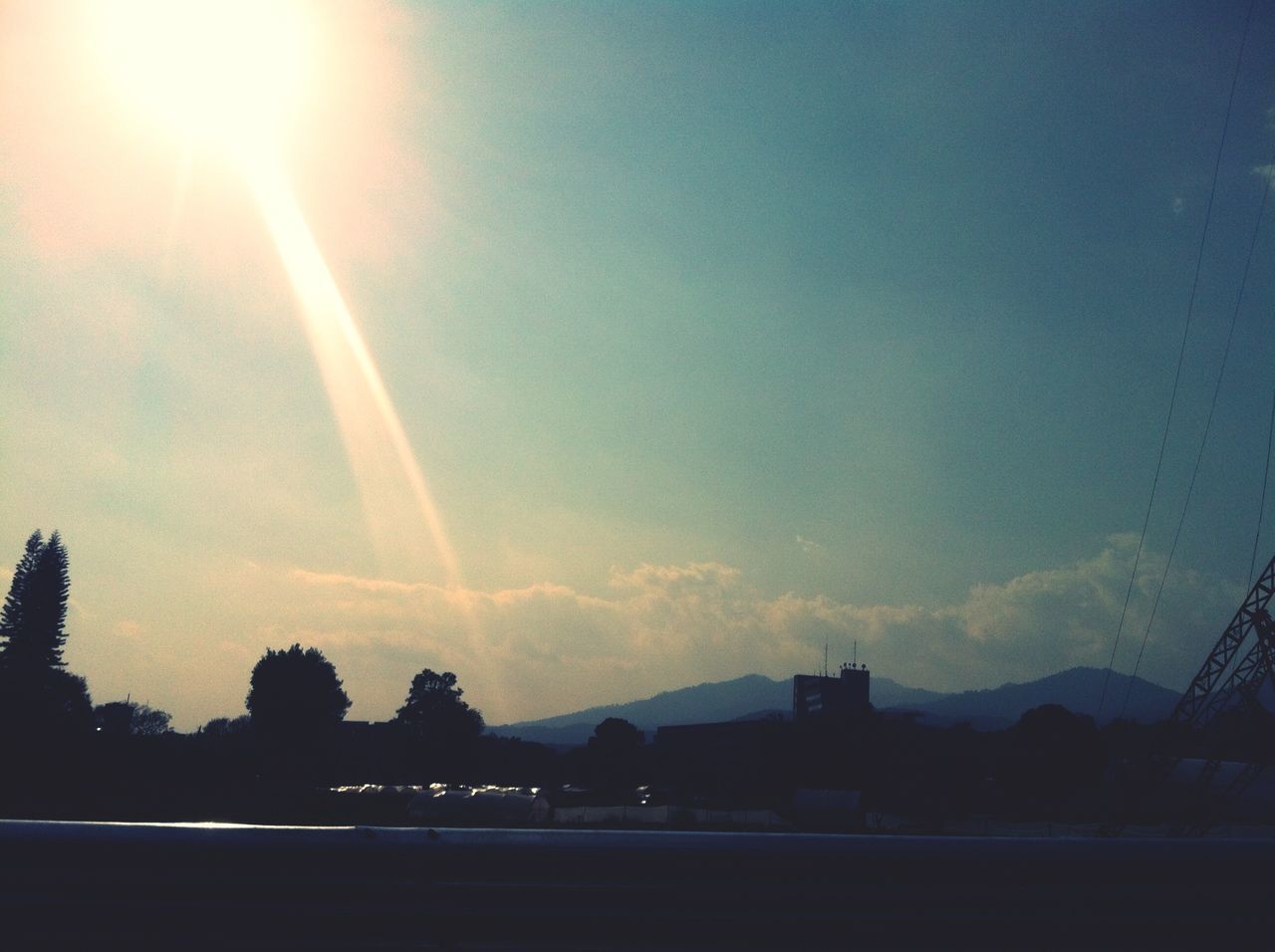 sky, road, scenics, beauty in nature, sun, sunbeam, landscape, transportation, nature, tranquility, sunset, tranquil scene, silhouette, lens flare, sunlight, cloud - sky, tree, outdoors, rainbow, no people