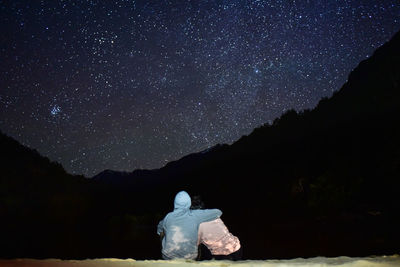 Rear view of man against mountain against sky at night