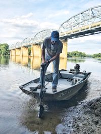 Man standing on boat in river against sky