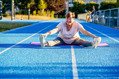 Portrait of young woman exercising on field