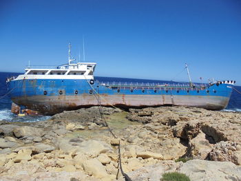 Ship moored on sea against clear blue sky