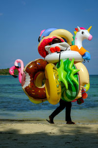 Multi colored balloons on beach against sky