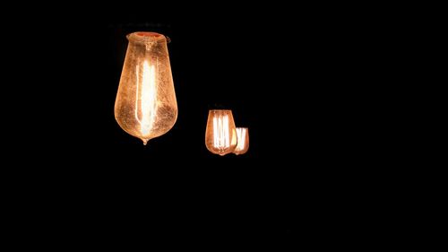 Low angle view of illuminated lamp against black background