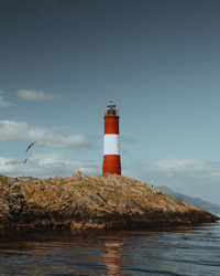 Lighthouse by sea against sky