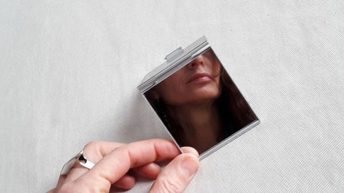 Close-up of woman holding hands against wall