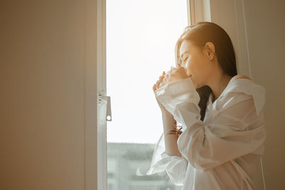 Side view of a young woman looking away at home