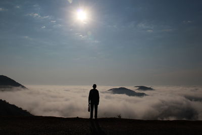 Rear view of man standing against cloudscape