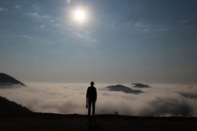 Rear view of silhouette man standing on land against sky 