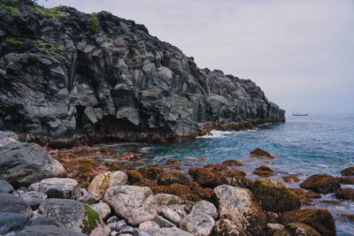 Scenic view of rocks by sea against sky