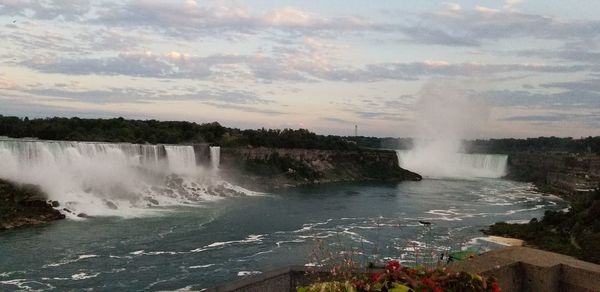 Scenic view of waterfall against cloudy sky