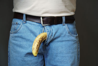 Rear view of man with banana wearing blue jeans