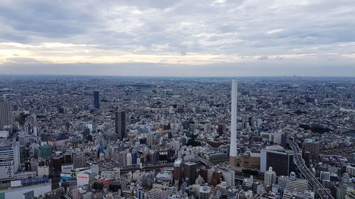 High angle view of city buildings against cloudy sky