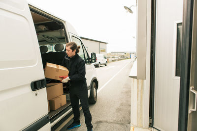 Manual worker unloading boxes from delivery van