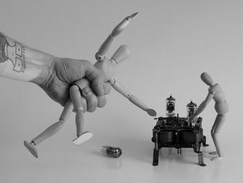 Close-up of hand holding cigarette against white background