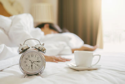 Close-up of coffee cup on bed at home