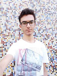 Portrait of young man standing against wall