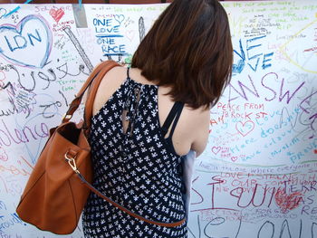 Rear view of woman writing on wall