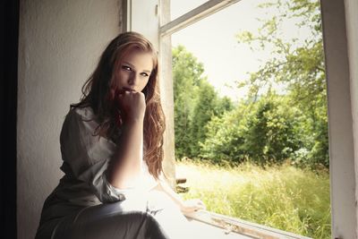 Portrait of young woman sitting by window