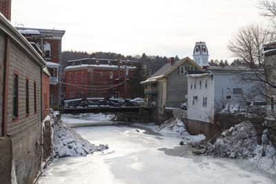 Snow covered houses by buildings against sky